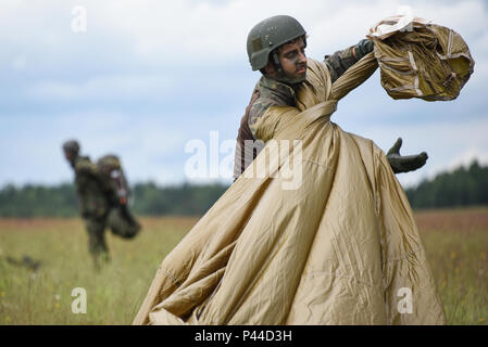 Eine niederländische Armee Fallschirmjäger packs sein Fallschirm nach dem Springen in Bunker Drop Zone in Grafenwöhr, Deutschland, 15. Juni 2016, während der Übung die schnelle Reaktion 16. Übung schnelle Reaktion ist eines der führenden militärischen Krisenreaktion Schulungen für multi-nationale zerstreuten Kräfte in der Welt. Die Übung ist so konzipiert, dass die Bereitschaft der Bekämpfung der Kern der U.S. Global Response Force - derzeit der 82nd Airborne Division 1st Brigade Combat Team - Schnelle-Antwort, Joint-gewaltsamen Eindringen und neben hoher Einsatzbereitschaft der Alliierten Streitkräfte in Europa zu verbessern. Schnelle Reaktion Stockfoto