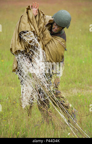 Eine niederländische Armee Fallschirmjäger packs sein Fallschirm nach dem Springen in Bunker Drop Zone in Grafenwöhr, Deutschland, 15. Juni 2016, während der Übung die schnelle Reaktion 16. Übung schnelle Reaktion ist eines der führenden militärischen Krisenreaktion Schulungen für multi-nationale zerstreuten Kräfte in der Welt. Die Übung ist so konzipiert, dass die Bereitschaft der Bekämpfung der Kern der U.S. Global Response Force - derzeit der 82nd Airborne Division 1st Brigade Combat Team - Schnelle-Antwort, Joint-gewaltsamen Eindringen und neben hoher Einsatzbereitschaft der Alliierten Streitkräfte in Europa zu verbessern. Schnelle Reaktion Stockfoto