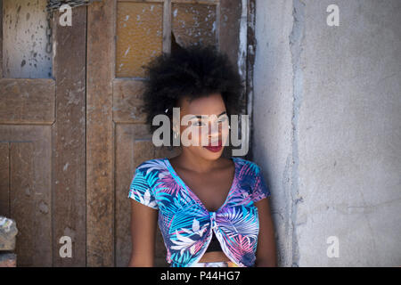 Ein afrikanisches Modell sitzt auf einer alten Mauer aus Stein und Holz- tür Stockfoto