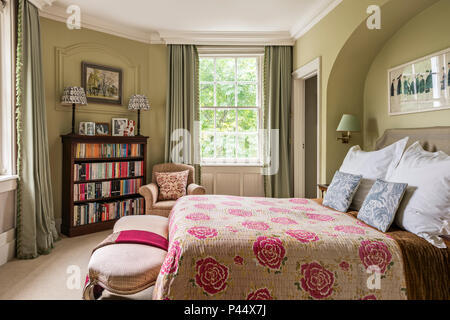 Rosa Blumenmuster gesteppten Decken auf dem Bett in der viktorianischen Haus mit Vintage Bücherregal Stockfoto