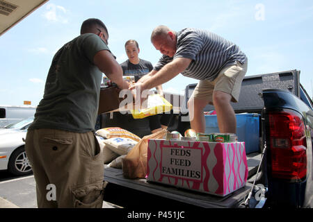 Lance Cpl. Benjamin Robinson, Links, ist ein Feld von Konserven von Navy lt Cmdr übergeben. Paul Greer, rechts, im Rahmen des jährlichen FBI-Agenten Feed Familien Nahrung bei Havelock, N.C., 22. Juni 2016. Da das Essen in 2009 begann, DOD Mitarbeiter gespendet haben 57,2 Millionen Pfund für Lebensmittel und andere unverderbliche Lebensmittel. Robinson ist ein Ingenieur Systeme Elektrik Techniker mit Marine Flügel Communications Squadron 28 und Greer ist der Kaplan für Marine Flugzeuge Gruppe 28. (U.S. Marine Corps Foto von Cpl. Jason Jimenez/Freigegeben) Stockfoto