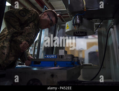 Staff Sgt. Tyler Herzog, 455Th Expeditionary Maintenance Squadron Metalle Techniker, strafft eine Klemme an einem Computer numerical control Mühle, Juni 09, 2016, Flugplatz Bagram, Afghanistan. Die CNC-Maschine erstellen können komplexe Flugzeugkomponenten aus Metall, das in der Regel unmöglich sein würde, konventionell zu machen. (U.S. Air Force Foto von älteren Flieger Justyn M. Freeman) Stockfoto