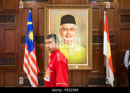 Mann hinter einem Portrait von Najib Razak, ehemaliger Premierminister von Malaysia, an der United Malays National Organisation (UMNO) Sitz im Putra World Trade Centre (PWTC) in Kuala Lumpur, Malaysia, am Dienstag, den 8. Dezember 2015. Stockfoto