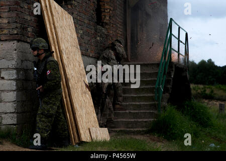 Ein kanadischer Soldat und Fallschirmjäger mit der 173Rd Airborne Brigade gegen eine Tür mit einem explosiven während einer Übung in Wedzryn, Polen, 15. Juni 2016, als Teil der Übung Anakonda 2016. Die Übung ist eine polnisch-led, multinationale Übung in Polen von Juni 7-17, an denen mehr als 31.000 Teilnehmer aus mehr als 20 Nationen. (U.S. Armee Foto von Sgt. 1. Klasse Whitney Hughes/Freigegeben). Stockfoto