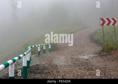 Mountain Pass Road mit kurvigen Straße Zeichen und Bäume im Nebel Landschaft - Rumänien Stockfoto