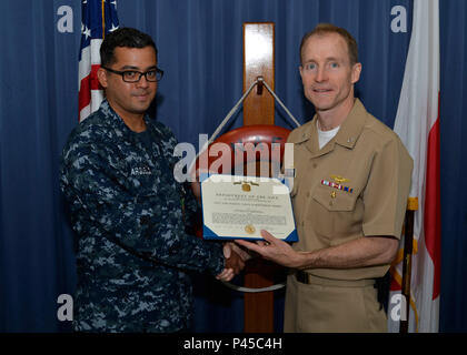 160630-N-OK 605-004 Misawa, Japan (30. Juni 2016) Elektroniker 1. Klasse Luis Argüello, aus Miami, erhält ein Navy und Marine Corps Leistung Medaille von Kapitän Keith Henry, kommandierender Offizier Naval Air Facility Misawa. (U.S. Marine Foto von Mass Communication Specialist 2. Klasse Samuel Weldin/Freigegeben) Stockfoto