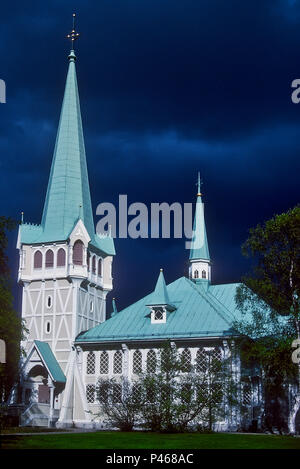 Eine leistungsstarke Sommer Sturm sammeln hinter die schöne sonnendurchflutete Kirche in Jokkmokk in Schweden Stockfoto