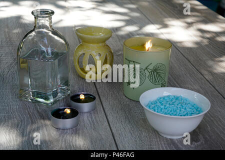 Eine Flasche, weiße Blüten, Badesalz und Kerzen, Entspannung im Freien auf einer hölzernen Tisch... Stockfoto