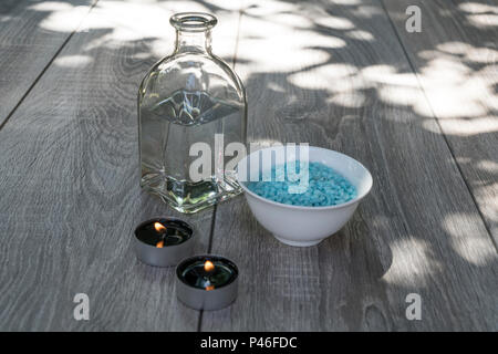 Eine Flasche, weiße Blüten, Badesalz und Kerzen, Entspannung im Freien auf einer hölzernen Tisch... Stockfoto