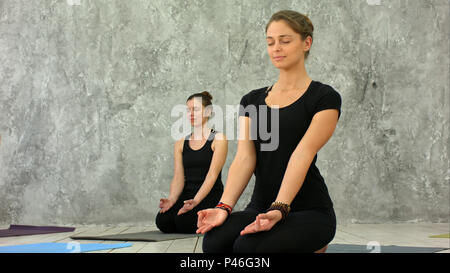 Schöne junge Frauen im Loft Innenraum, Yoga Übung, sitzen in einfache Asanas für Meditation, mudra Geste Stockfoto