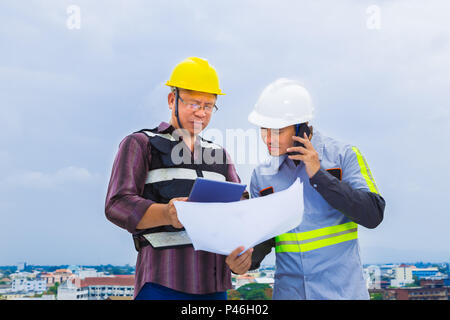 Asiatische Bauingenieur arbeiten mit seinem Meister, während sie sein Handy an der Baustelle, gut für Teamarbeit und Engineering Thema Stockfoto