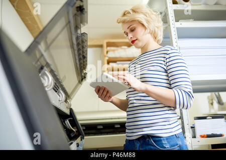 Frau mit Tablet in der Nähe der Drucker im Büro Stockfoto