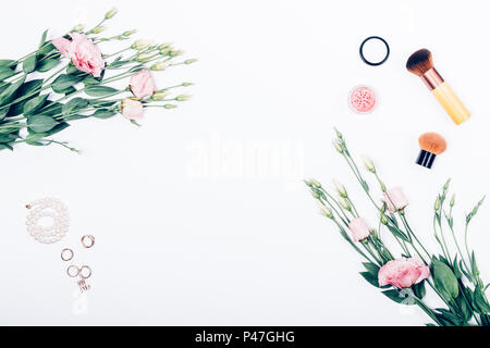 Rahmen des dekorativen Frauen Kosmetik und Schmuck mit eustoma Blumen, Ansicht von oben. Flach Blumenschmuck auf weißem Hintergrund. Stockfoto