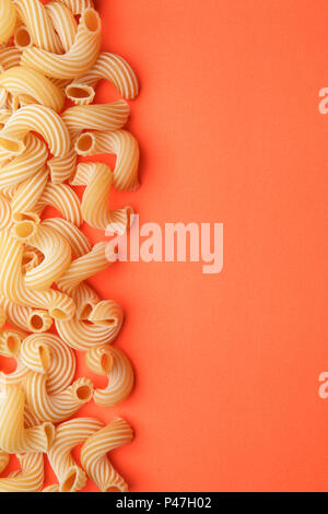 Pasta Penne Rigate auf orange Hintergrund Stockfoto