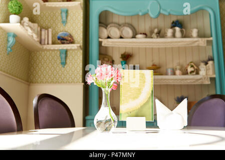 Frische Rosen in einer Vase auf einem weißen Tisch in hellem Sonnenlicht. Stockfoto