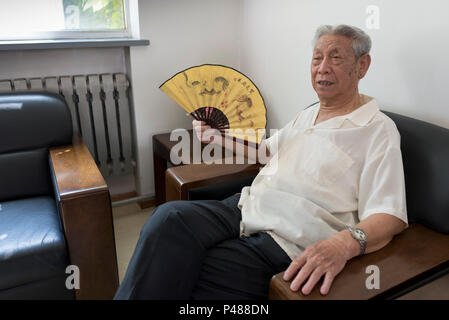 Pensionierter Mann entspannt sich mit Ventilator im Xin Wai Bei Community Center Beijing, China Stockfoto