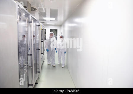 Gruppe der Arbeiter in Schutzkleidung in einem sterilen Raum einer Fabrik zu Ehren Arzneimittel zu entwickeln und Stockfoto