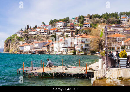 Ohrid, Republik Mazedonien: Menschen sitzen in einem Restaurant draußen von einem Pier am See mit Blick auf die Altstadt, die zum UNESCO-Welterbe gehört in b aufgeführt sind. Stockfoto