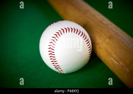 White baseball ball und Holz- bit auf grünem Filz Hintergrund isoliert Stockfoto