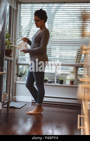 Junge schwangere Frau, Bewässerung der Pflanzen Stockfoto