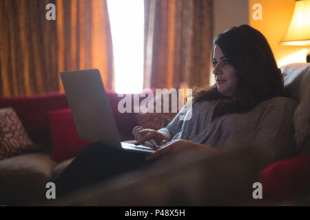 Weibliche vlogger sitzen auf dem Sofa, während mit Laptop Stockfoto