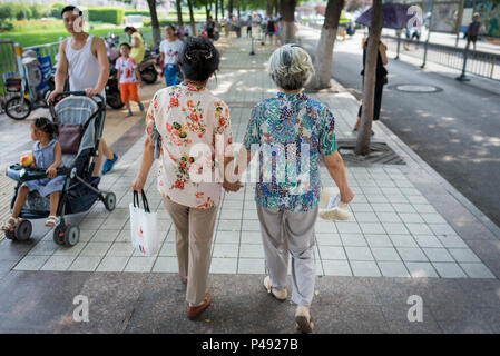 Erwachsene Tochter hält der älteren Mutter während der Spaziergang im Stadtpark, Quancheng Square, Taian, Shandong Province, China Stockfoto