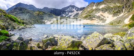 Panorama von Rila Mountain Lake und Mussala Gipfel auf einer schneebedeckten Landschaft mit Vordergrund Felsen Stockfoto