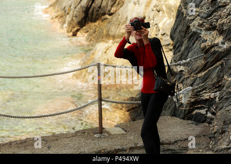 Frau touristische Fotografen - videofilmer offen Schießen gegen Rocky seeküste Hintergrund im Cinque Terre, Italien Stockfoto