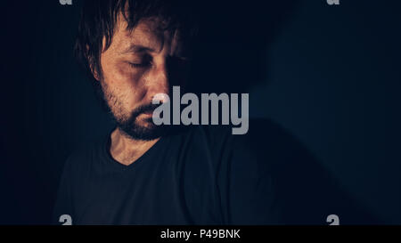 Psychische Gesundheit und Depression Konzept, traurig, deprimiert man schmollt in dunklen Innenraum Stockfoto