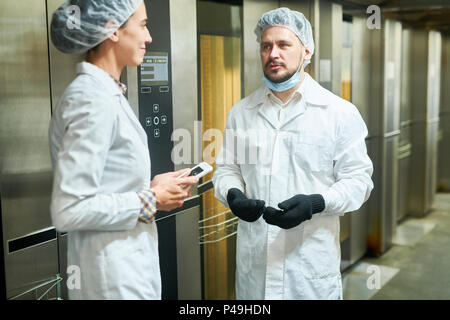 Menschen in Laborkitteln sprechen in der Nähe von Aufzügen Stockfoto