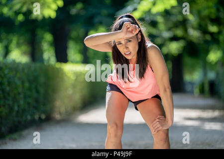 Junge schöne und attraktive Sport Frau in Runner Sportswear atmen Keuchen und Pause machen müde und nach dem Lauftraining auf Autu erschöpft Stockfoto
