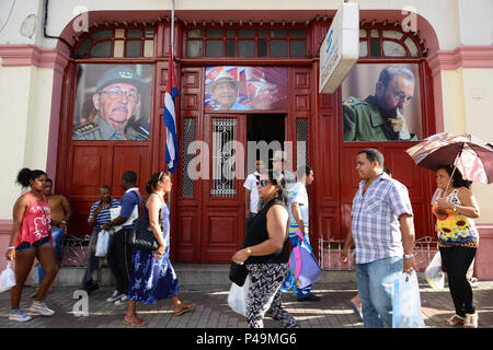 SANTIAGO DE CUBA, Kuba - 29. NOVEMBER 2016: Kubaner auf Santiago de Cuba Straßen auf die Schränke Porträts von Fidel und Raul Castro suchen Stockfoto