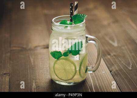 Kalte Mojito Cocktail mit Eis, Zitrone und Minze in Mason Jar auf rustikalen dunklen Hintergrund als Sommer Konzept Stockfoto