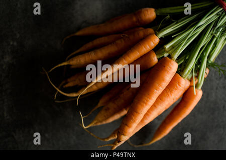 Organische Nantes Karotten auf rustikalen dunklen Hintergrund. Frische Superfood Gesund Essen Konzept. Stockfoto