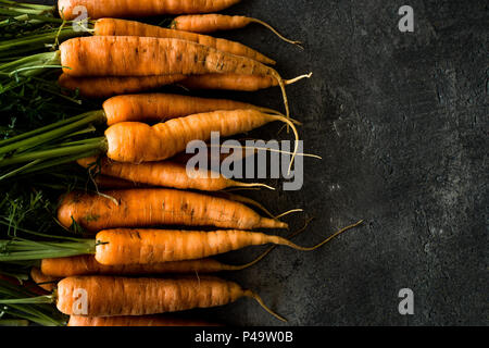 Organische Nantes Karotten auf rustikalen dunklen Hintergrund. Frische Superfood Gesund Essen Konzept. Stockfoto