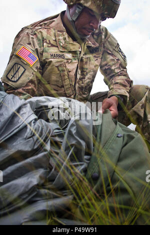 Chief Warrant Officer John Harris III, 824Th Quartermaster Unternehmen, packt sein Fallschirm nach einem erfolgreichen Sprung auf St. Mere Eglise Drop Zone in der Nähe von Fort Bragg, N.C. am 25. Juni 2016. Die 824Th support für den Betrieb zur Verfügung gestellt, der von der US-Armee die zivilen Angelegenheiten & psychologische Operations Command (Airborne). USACAPOC (A), eine Armee finden Einheit, führt luftgestützten Hilfsaktionen in der Auftragswährung und Leistungsfähigkeit zu erhalten. USACAPOC (A) unterstützt die Armee und der gemeinsamen Kraft mit strategischen, operativen und taktischen zivilen Angelegenheiten, militärische Informationen Support und Information Funktionen acr Stockfoto