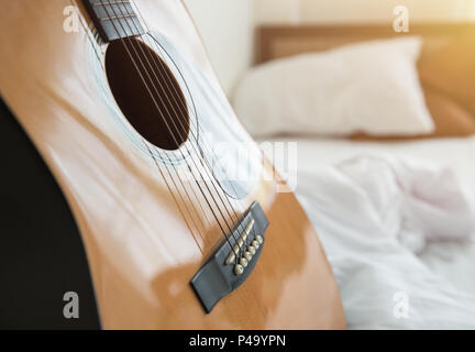 Musik im Schlafzimmer morgen Konzept. Gitarre mit weißer Bettwäsche. Stockfoto