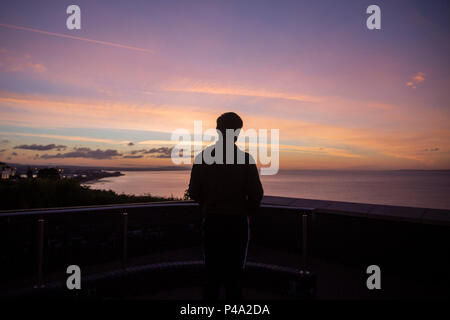 Penarth, Wales, Großbritannien, 21. Juni 2018. Ein Mann wartet auf die Sonne im Hochsommer über den Kanal von Bristol am längsten Tag des Jahres zu steigen. Credit: Mark Hawkins/Alamy leben Nachrichten Stockfoto