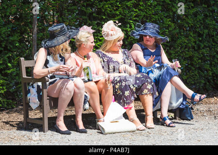 Ascot, Berkshire, Großbritannien. 21st. Juni 2018. Racegoers kommen in Ascot in ihren Hüten und Raffinerie für Ladies Day in Royal Ascot, während sie ihren Weg zu der Veranstaltung machen. Fashion on Ladies Day Royal Ascot - vier Frauen sitzen auf der Bank in der Sonne und genießen einen Drink. Quelle: Carolyn Jenkins/Alamy Live News Stockfoto