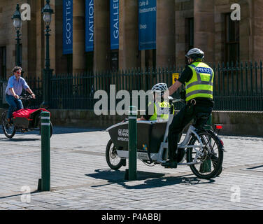 Edinburgh, Schottland, Vereinigtes Königreich, 21. Juni 2018. Der Hügel der National Gallery war heute Morgen für Fahrzeuge gesperrt, damit man bei einer von Electron Wheels organisierten Veranstaltung Elektrofahrräder ausprobieren konnte. Zwei Polizisten probieren ein Urban Arrow Elektrofahrrad aus Stockfoto