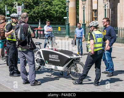 Edinburgh, Schottland, Vereinigtes Königreich, 21. Juni 2018.der Boden des Hügels in der Nationalgalerie war heute Morgen für Fahrzeuge gesperrt, damit die Leute in einer von Electron Wheels organisierten Veranstaltung Elektrofahrräder ausprobieren konnten. Polizisten, ein Polizist und eine Polizistin unterhalten sich über das Urban Arrow Frachtrad Stockfoto