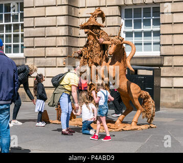 Edinburgh, Schottland, Vereinigtes Königreich, 21. Juni 2018. Eine Street Performer in einem Levitation handeln gekleidet, wie Gandalf der Zauberer mit einem Einhorn Passanten auf der Royal Mile während der Sommersaison zu unterhalten. Eine Frau und Kinder von der Straße handeln unterhalten wie Leute von Pass Stockfoto