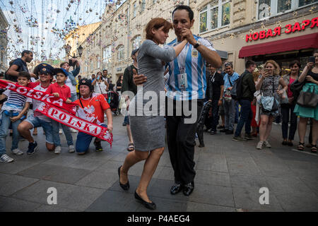 Moskau, Russland. Juni 2018. Ein Paar tanzt argentinischen Tango auf dem Hintergrund der polnischen Fußballfans auf Nikolskaja Straße im Zentrum von Moskau während der FIFA Fußball-Weltmeisterschaft Russland 2018 Stockfoto