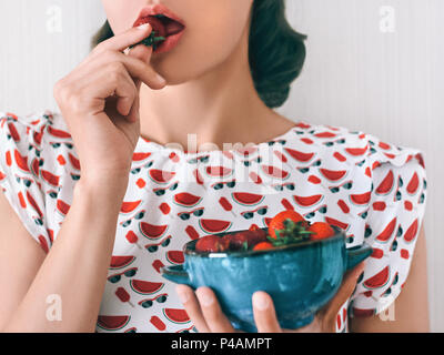 Frische reife Erdbeere Mädchen in einem hellen Kleid ist eine blaue Schüssel mit Erdbeeren Nahaufnahme Stockfoto