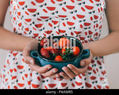 Frische reife Erdbeere Mädchen in einem hellen Kleid ist eine blaue Schüssel mit Erdbeeren Nahaufnahme Stockfoto