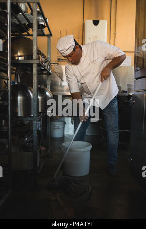 Männliche baker Reinigung Boden mit Mop Stockfoto