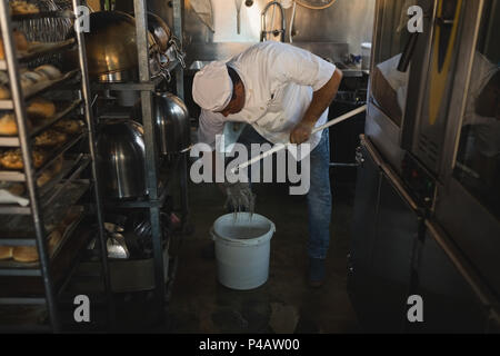 Männliche baker Reinigung Boden mit Mop Stockfoto