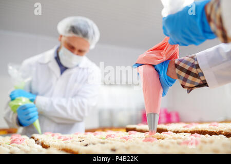 Professionelle Bäcker dekorieren Kuchen mit Sahne Stockfoto