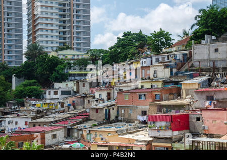 Bunte Häuser der armen Bewohner von Luanda, Angola. Im Hintergrund die Hochhäuser der Reichen Stockfoto
