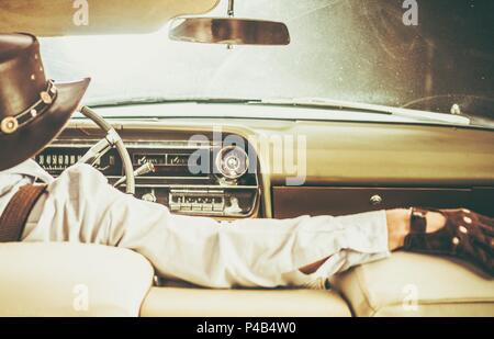 Cowboy auf dem Weg in die klassische Convertible amerikanische Fahrzeug. Stockfoto